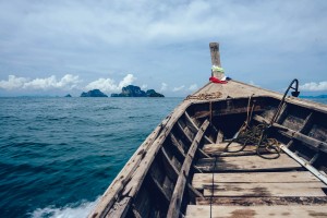 Brown Wooden Boat on Sea Overlooking Rocky Island